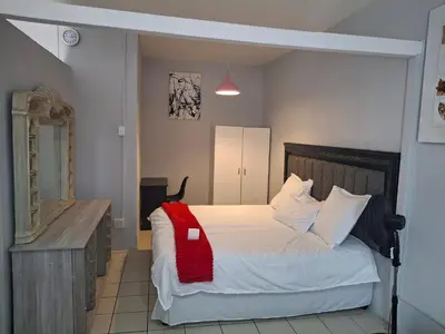 a bedroom with a bed with a red blanket on it at Comfort and calm zone in Cape Town
