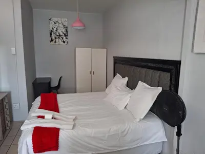 a bedroom with a white bed with a red blanket at Comfort and calm zone in Cape Town