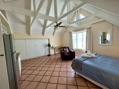 a bedroom with a bed and a chair in a room at The Loft House in Cape Town