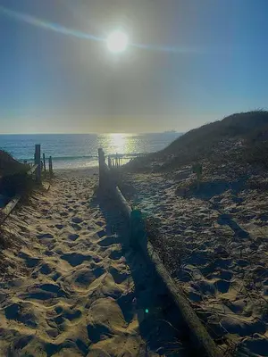 a sandy beach with the sun rising over the ocean at The Loft House in Cape Town