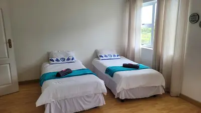two twin beds in a room with a window at Judea Accommodation in Bettyʼs Bay