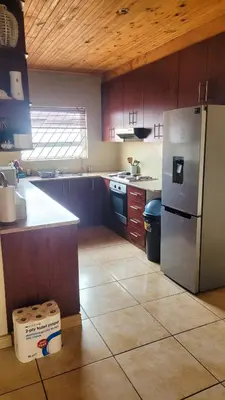 a kitchen with a stainless steel refrigerator and wooden cabinets at Judea Accommodation in Bettyʼs Bay