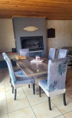 a dining room table with chairs and a fireplace at Judea Accommodation in Bettyʼs Bay