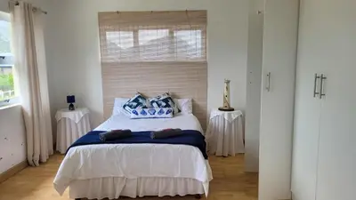 a bedroom with a bed with blue pillows on it at Judea Accommodation in Bettyʼs Bay