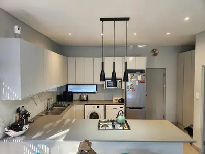 a kitchen with white cabinets and a refrigerator at St James home in Somerset West
