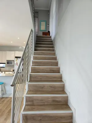 a staircase in a house with white walls and wooden floors at St James home in Somerset West