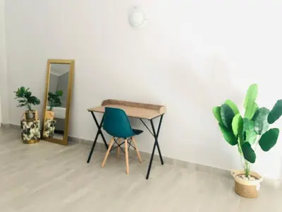 a table and a chair in a room with plants at Loft apartment by the lake in Cape Town