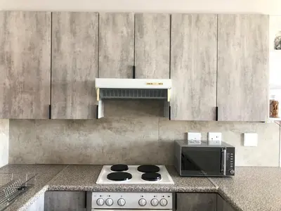 a kitchen with a stove and a microwave at Loft apartment by the lake in Cape Town