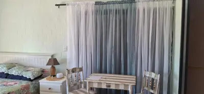 a bedroom with a bed and a table and a crib at Arendsnest Self Catering in Gordonʼs Bay