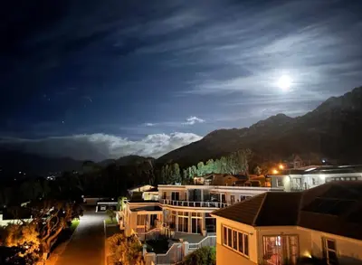 a view of a house at night with the moon at Arendsnest Self Catering in Gordonʼs Bay