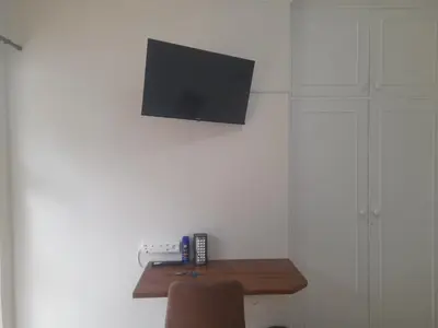 a room with a table with a television on a wall at Cornerstone Guesthouse Drostdy in Panorama