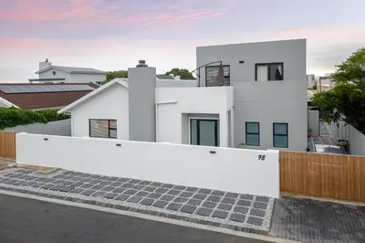 a white house with a white wall and stairs at Studio 98 - 300m from cliff path in Hermanus
