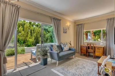 a living room with a chair and a desk and large windows at Whale Watchers Gordons Bay in Gordonʼs Bay