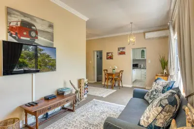 a living room with a blue couch and a tv at Whale Watchers Gordons Bay in Gordonʼs Bay