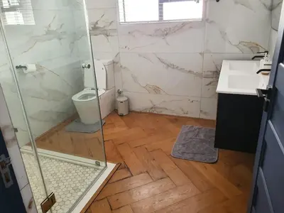 a bathroom with a shower and a toilet and a sink at Classy 3 storey house in Gordonʼs Bay
