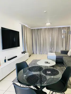 a living room with a couch and a table and chairs at Altin Pearl Luxury Apartment in Cape Town