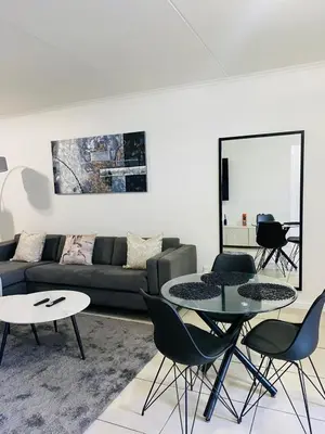 a living room with a couch and a table and chairs at Altin Pearl Luxury Apartment in Cape Town