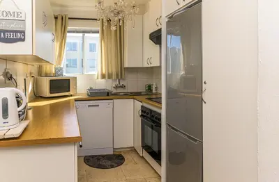 a kitchen with white cabinets and a refrigerator at Oceanfront Escape with Spacious Balcony Hermanus in Hermanus