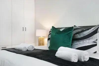 a bedroom with a bed with a green pillow and towels at Gordonia 10 in Cape Town