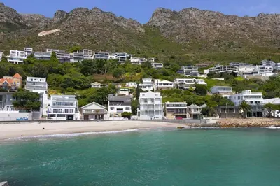 a group of houses on a beach next to the water at Gordonia 10 in Cape Town