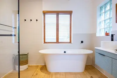 a white bath tub in a bathroom with a window at Onrus Island Milkwood Sanctuary in Hermanus