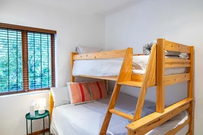 a bedroom with two bunk beds and a window at Onrus Island Milkwood Sanctuary in Hermanus