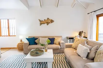 a living room with two couches and a table at Onrus Island Milkwood Sanctuary in Hermanus