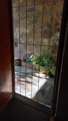 a glass door with plants in a stone wall at 'The Cape Robin' studio apartment in Hoheizen