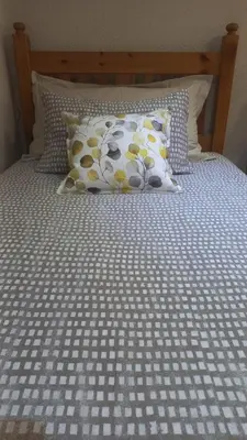 a bed with a white and yellow bedspread and pillows at 'The Cape Robin' studio apartment in Hoheizen