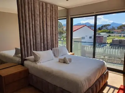 a bedroom with two beds and a large window at Classy 3 storey house in Gordonʼs Bay