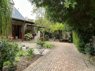 a brick walkway next to a house with a patio at Swallows Cottages in Hermanus