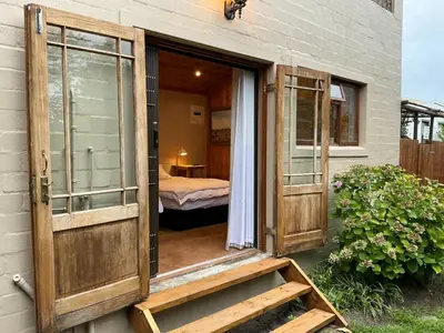 an open door of a house with a bedroom at Swallows Cottages in Hermanus