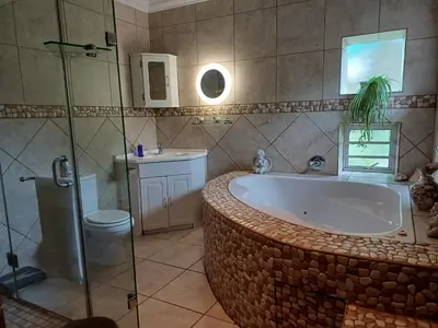 a bathroom with a large bath tub and a toilet at A Jungle House in Somerset West