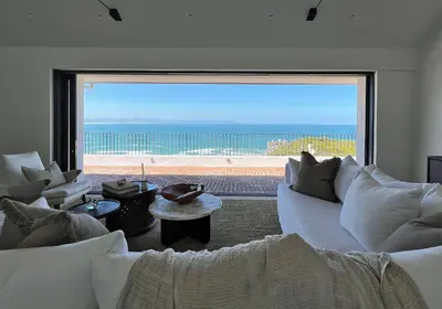 a living room with a white couch and a large window at Hermanus Seafront Villa - Sophie's Rock in Hermanus