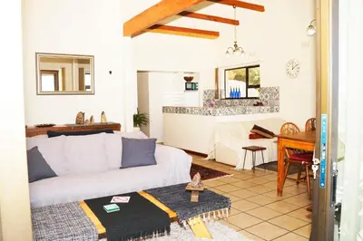 a living room with a white couch and a piano at View Panoramica Self-Catering Apartment in Gordonʼs Bay