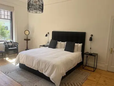 a bedroom with a large white bed with a black headboard at The Alma House 1900 in Cape Town