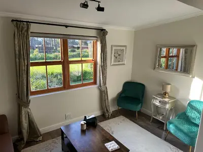 a living room with a table and a window at The Cottage - a tranquil hideaway in Somerset West