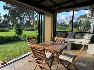 a patio with a table and two chairs and a couch at The Cottage - a tranquil hideaway in Somerset West
