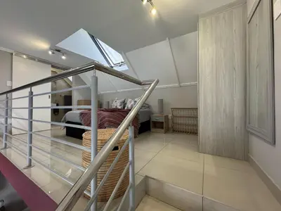 a bedroom with a bed and a staircase in a house at Stylish Loft apartment in the heart of Durbanville in Durbanville