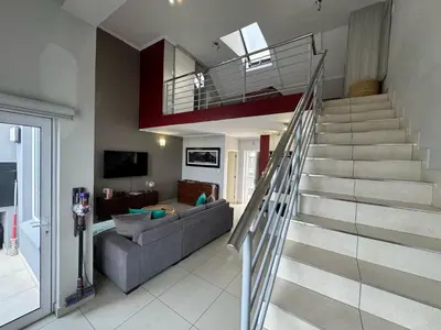 a living room with a staircase in a house at Stylish Loft apartment in the heart of Durbanville in Durbanville