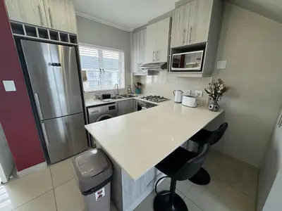 a small kitchen with a counter and a refrigerator at Stylish Loft apartment in the heart of Durbanville in Durbanville
