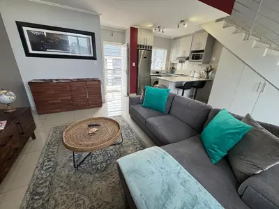a living room with a couch and a table at Stylish Loft apartment in the heart of Durbanville in Durbanville