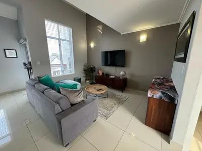 a living room with a couch and a tv at Stylish Loft apartment in the heart of Durbanville in Durbanville