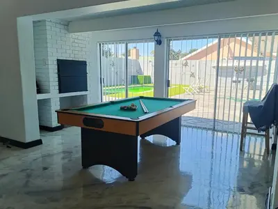 a pool table in a living room with a view of a patio at Frangipani House in Goodwood