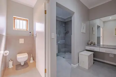 a white bathroom with a toilet and a shower at Lawaaiwaters in Hermanus