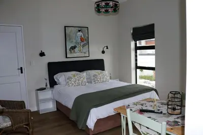 a bedroom with a bed and a table and a window at Little Nest Self-Catering in Hermanus