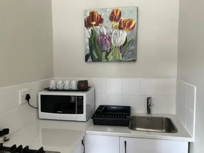 a kitchen counter with a microwave and a painting of tulips at Little Nest Self-Catering in Hermanus