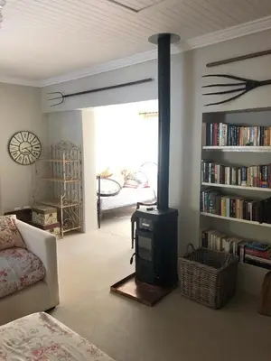 a living room with a wood stove in a living room at Charming Rose Cottage in Greyton