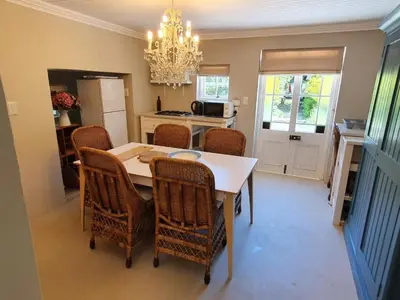 a kitchen with a dining table and chairs and a chandelier at Charming Rose Cottage in Greyton