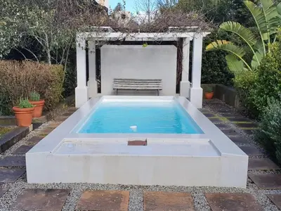 a swimming pool with a bench in a garden at Charming Rose Cottage in Greyton